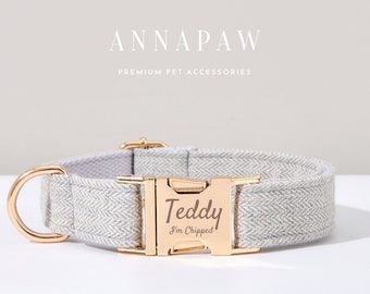 May include: A gray herringbone dog collar with a gold buckle. The buckle is engraved with the name "Teddy" and the text "I'm Chipped".