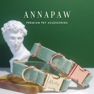 May include: Two green velvet dog collars with gold and rose gold hardware. The collar on top has a rose gold buckle and the collar on the bottom has a gold buckle with the name "Ruby" engraved on it.