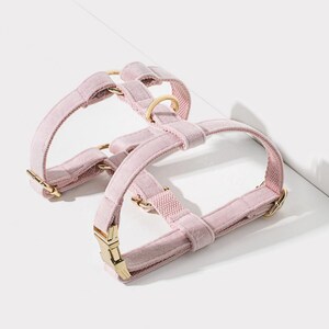 Puede incluir: Un arn&eacute;s para perro de terciopelo rosa con herrajes de metal dorado. El arn&eacute;s tiene dos correas ajustables y un cierre de hebilla.