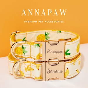 May include: Two dog collars with a white background and yellow pineapple and banana patterns. The collars have gold buckles and the words "Pineapple" and "Banana" are printed on the buckles.