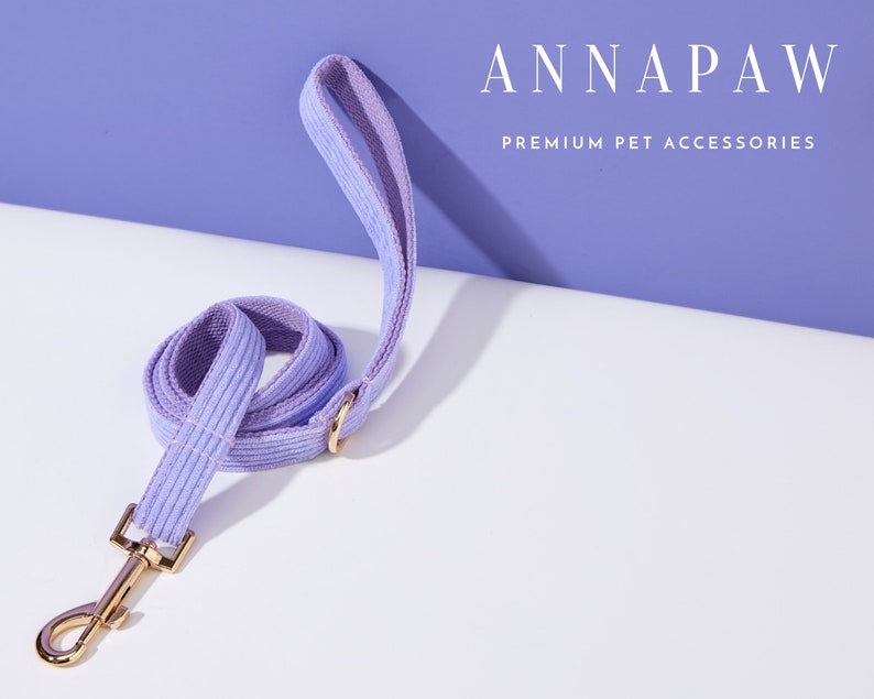 May include: A lavender corduroy dog leash with a gold metal clasp.  ANNAPAW PREMIUM PET ACCESSORIES is printed in white text on a purple background.