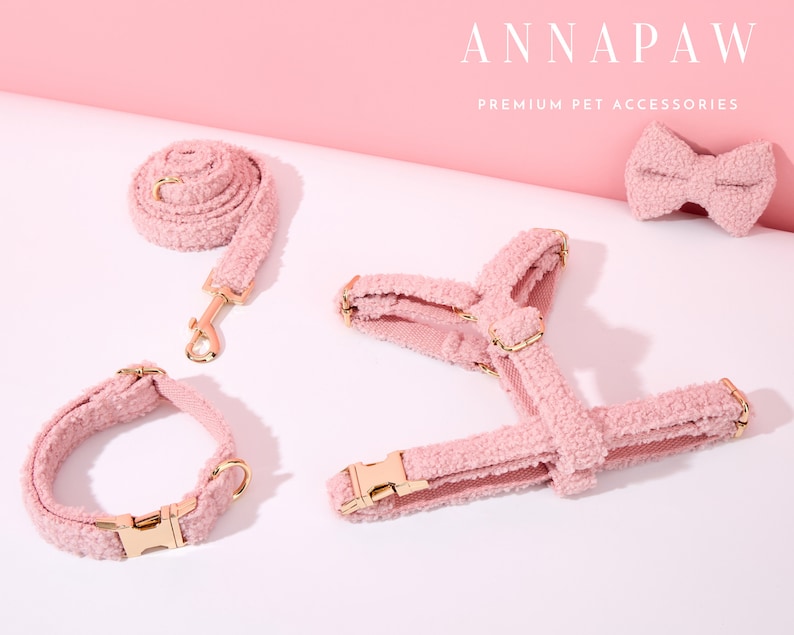 K&ouml;nnte beinhalten: Ein rosa flauschiges Hundegeschirr, Halsband und Fliege. Das Set besteht aus weichem, pl&uuml;schem Material und verf&uuml;gt &uuml;ber goldene Beschl&auml;ge. Der Text "ANNAPAW PREMIUM PET ACCESSORIES" ist in der oberen rechten Ecke des Bildes sichtbar.