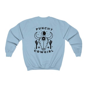 May include: Light blue sweatshirt with a black graphic of a cow skull, cacti, stars, and the text "Punchy Cowgirl".