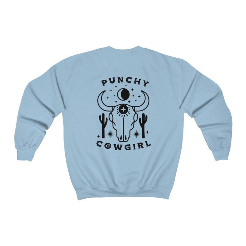May include: Light blue sweatshirt with a black graphic of a cow skull, cacti, stars, and the text "Punchy Cowgirl".