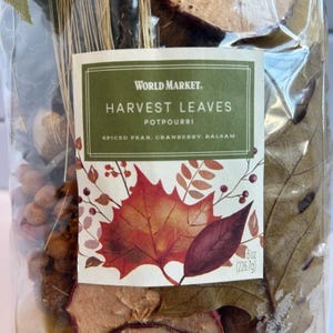 May include: A clear plastic bag containing Harvest Leaves potpourri by World Market. The label features a red maple leaf illustration and text reading Spiced Pear, Cranberry, Balsam. The package net weight is clearly printed as 8 oz.
