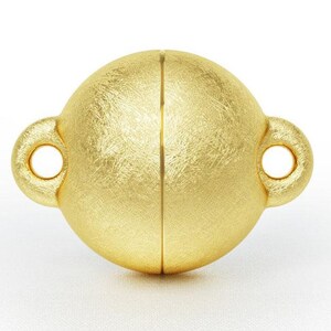 May include: A gold-toned magnetic clasp for jewelry making. The clasp is round with a textured surface and two small loops on either side.