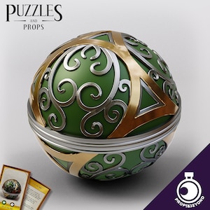 May include: A green, gold and silver decorative sphere with intricate swirling patterns. The sphere is a puzzle prop.