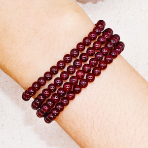 May include: A stack of red gemstone bracelets. The bracelets are made of small, round beads.