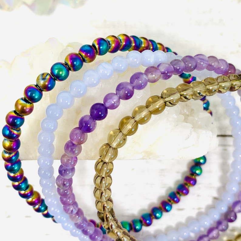 Anti Anxiety Crystal Bracelets 4mm round beads of Amethyst, Blue Lace Agate, Smoky Quartz, Rainbow Hematite on white background. Dainty stackable crystal bracelet design with intention of relieving stress and worry.