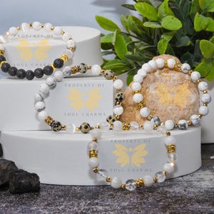 May include: Three bracelets with different beads and gold accents. The bracelets are stacked on top of each other on a white surface. The bracelets are labeled "Property of Soul Charms".