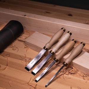 May include: Four wood carving chisels with wooden handles and brass accents. The chisels are labeled "Boddo 24 Ukraine 8.00", "Boddo 20 Ukraine 8.00", "Boddo 12 Ukraine 8.00", and "Boddo 12 Ukraine 8.00".