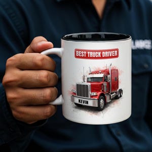 Peut inclure: Mug en céramique blanche avec intérieur noir, orné d'une illustration de semi-remorque rouge. Le mug porte l'inscription "BEST TRUCK DRIVER" et le nom "KEVIN" sur le devant.