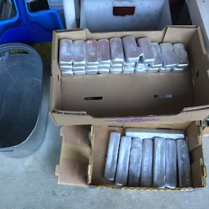 May include: Two cardboard boxes filled with silver-colored metal bars. The bars are stacked neatly in the boxes.