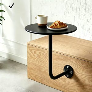 Puede incluir: Una taza de cerámica blanca con un asa negra y el texto "But First, Coffee" en un estilo manuscrito. La taza está sobre una superficie blanca. La taza mide 10 cm de alto.