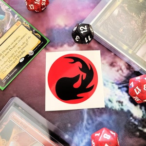 Könnte beinhalten: Ein roter Kreisaufkleber mit einem schwarzen Drachensymbol im Inneren. Der Drache ist mit seinem Schwanz im Maul zusammengerollt. Der Aufkleber befindet sich auf einem weißen Hintergrund.