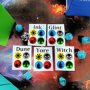 May include: Five white stickers with black text and symbols. The stickers are labelled "Ink", "Glint", "Dune", "Yore", and "Witch". Each sticker has four symbols: a sun, a skull, a flame, and a tree.