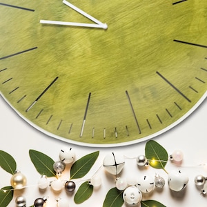 May include: A green clock with black markings and white hands, surrounded by white and silver bells and green leaves.
