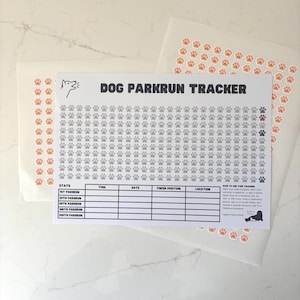 May include: A white paper Dog Parkrun Tracker sheet featuring a dog icon, a grid of numbered paw prints, and a stats table. The tracker includes instructions and a sheet of orange paw print stickers for marking progress during runs.