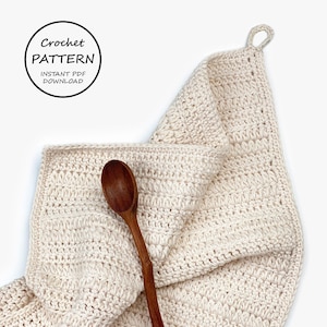 May include: A crocheted dishcloth in a cream color with a wooden spoon on top. The dishcloth has a loop for hanging. The text "Crochet Pattern Instant PDF Download" is in a circle at the top of the image.