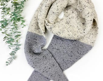 Puede incluir: Una bufanda triangular de punto con un diseño bicolor que presenta una sección superior de color crema moteado y una sección inferior de color gris moteado. El accesorio está elaborado con una textura de punto bobo y una transición clara.