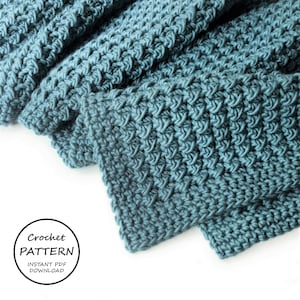 Könnte beinhalten: Eine tealblaue gehäkelte Decke mit einem strukturierten Stichmuster. Die Decke ist gefaltet und über eine weiße Oberfläche gelegt. Der Text "Crochet Pattern Instant PDF Download" ist in der linken unteren Ecke des Bildes sichtbar.