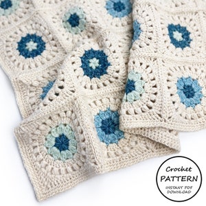 May include: A crocheted blanket with a cream background and blue and green floral motifs. The blanket is folded in half and the text "Crochet PATTERN INSTANT PDF DOWNLOAD" is visible in the lower right corner.