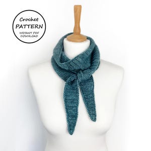 Könnte beinhalten: Ein türkisfarbener Häkelschal wird auf einer weißen Schaufensterpuppe präsentiert. Der Schal ist am Hals geknotet, wobei die Enden herunterhängen. Der Text "Crochet Pattern Instant PDF Download" befindet sich in einem schwarzen Kreis oben links.