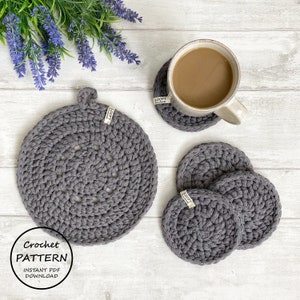 May include: A set of four gray crocheted coasters and a larger gray crocheted pot holder with a loop handle. The coasters and pot holder have a small tag that says "Loopy Handmade".