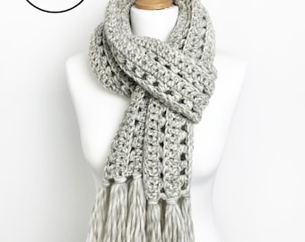 May include: A gray crocheted scarf with long fringe tassels. The scarf is draped over a white mannequin. The text "Crochet Pattern Instant PDF Download" is in a black circle.