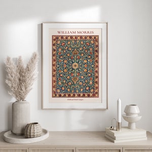 May include: A framed print of a vintage William Morris Holland Park Carpet design. The carpet features a blue background with intricate floral patterns in shades of red, yellow, and green. The print is framed in a white frame and has a white mat.