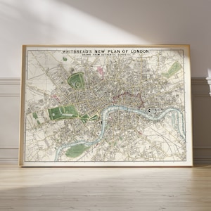 May include: A vintage map of London, England, titled "Whitbread's New Plan of London, Drawn from Authentic Surveys". The map is framed in a light wood frame and is displayed on a light wood floor.