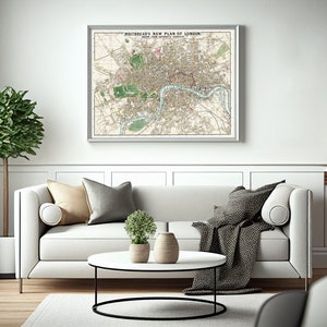 May include: A white sofa with beige and gray throw pillows and a black throw blanket. A vintage map of London titled "Whitebread's New Plan of London" hangs on the wall above the sofa. A round coffee table with a white top and black metal base sits in front of the sofa.