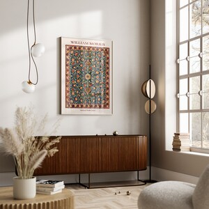 May include: A poster featuring a vintage design of a rug with a floral pattern. The poster is titled "William Morris" and has the text "Holland Park Carpet" at the bottom. The poster is hanging on a white wall above a wooden cabinet.