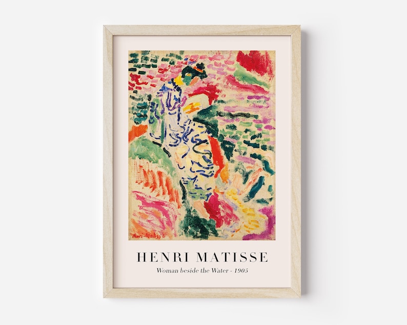 May include: A framed print of a painting by Henri Matisse titled "Woman beside the Water - 1905". The painting features a woman in a white and blue dress standing in a landscape of colorful brushstrokes.