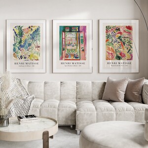 May include: Three framed art prints featuring abstract paintings by Henri Matisse. The prints are hung on a white wall above a white sofa with pillows.