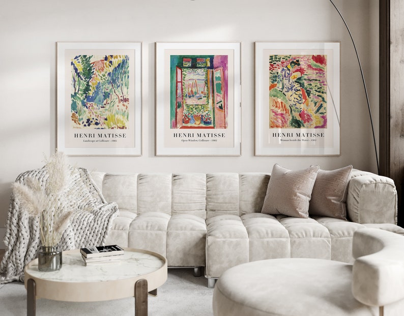 May include: Three framed art prints featuring abstract paintings by Henri Matisse. The prints are hung on a white wall above a white sofa with pillows.