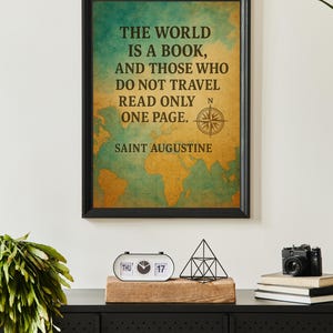 May include: Framed wall art with a black border, featuring a world map and the quote: "THE WORLD IS A BOOK, AND THOSE WHO DO NOT TRAVEL READ ONLY ONE PAGE." A compass rose is also included. A black camera, books, and a calendar are on a black cabinet.