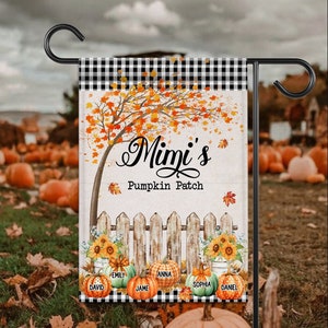 May include: A garden flag with a black and white checkered top border. The flag features a fall-themed design with a tree, pumpkins, and the text "Mimi's Pumpkin Patch." Names are printed on the pumpkins. The flag is displayed on a black metal stand.