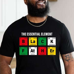 May include: Black t-shirt with a graphic of the periodic table elements spelling out the word "BLACK" with the text "THE ESSENTIAL ELEMENT" above it.