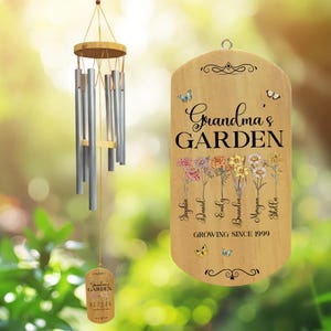 May include: A wooden sign with the text "Grandma's GARDEN" and a floral design. The sign also includes the names "Sophia, Daniel, Emily, Beau, Morgan, Stella" and the text "Growing Since 1999". A silver wind chime hangs above the sign.