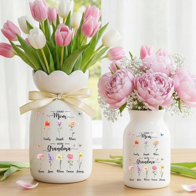 May include: Two white ceramic vases with floral arrangements. One vase holds pink and white tulips, the other holds pink peonies. Both vases have a ribbon and the text "First Mom Now Grandma" with names and flower illustrations.