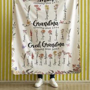 May include: A white floral blanket with the words "Mom Growing since 1977", "Grandma Growing since 1999", and "Great Grandma Growing since 2022" along with a list of names.