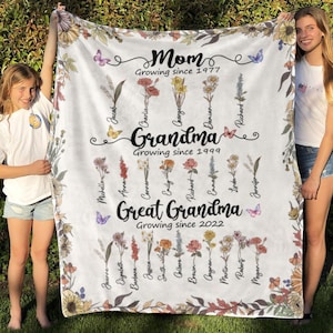 May include: A white fleece blanket with a floral design and names of family members. The text reads "Mom Growing since 1977", "Grandma Growing since 1999", and "Great Grandma Growing since 2022".