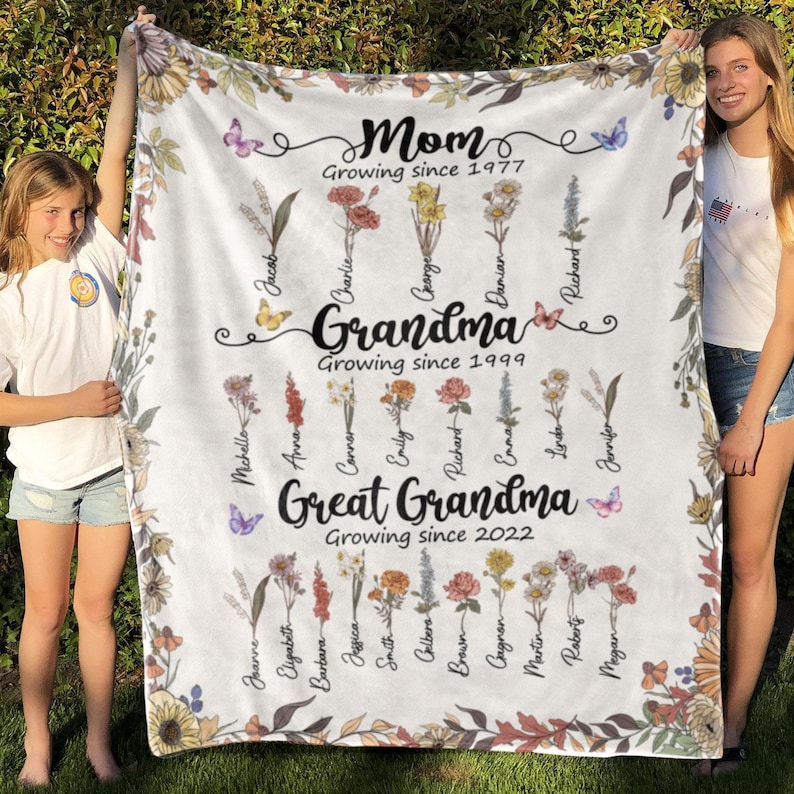May include: A white fleece blanket with a floral design and names of family members. The text reads "Mom Growing since 1977", "Grandma Growing since 1999", and "Great Grandma Growing since 2022".