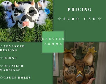 May include: A cow mask with black and white spots, pink nose, and small orange horns. The mask is on green grass. A second mask, a cat, is held in a hand. The image includes the text "SPECIES COMMS" and "ADVANCED DESIGNS".
