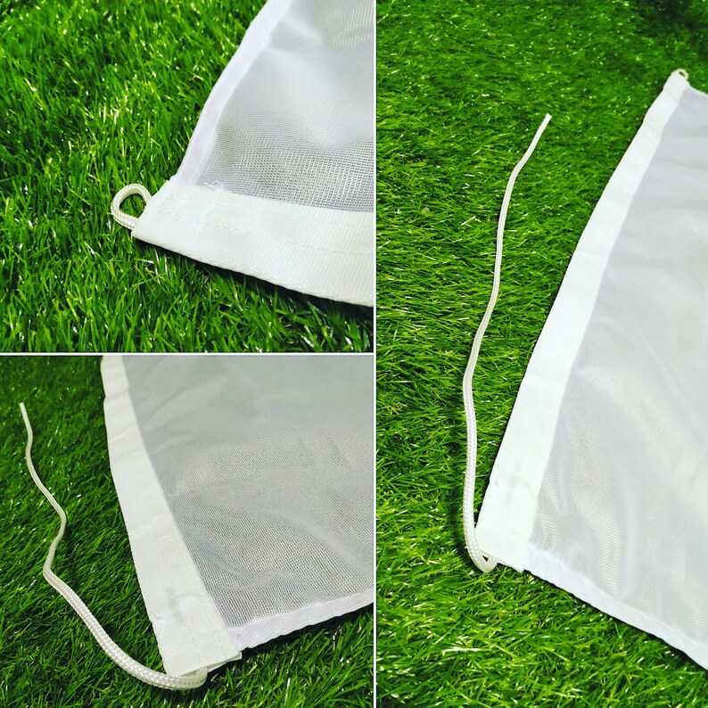 Puede incluir: Primer plano de una bandera blanca con una cuerda blanca y un borde blanco. La bandera est&aacute; hecha de un material transparente. La bandera est&aacute; sobre una superficie verde.