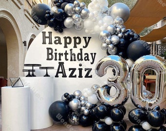 Könnte beinhalten: Schwarze, silberne und weiße Ballons, die in einem Halbkreis um einen weißen Hintergrund mit dem Text "Happy Birthday Aziz" und der Zahl "30" in silbernen Ballons angeordnet sind.
