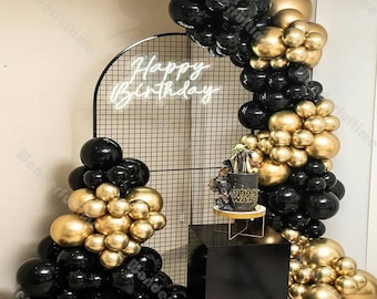 Könnte beinhalten: Ein schwarzer und goldener Ballonbogen mit einem Neon-Schild, auf dem "Happy Birthday" steht. Der Bogen ist mit schwarzen und goldenen Ballons geschmückt, und in der Mitte des Bogens steht eine Torte. Die Torte ist mit einem Star Wars-Motiv verziert.