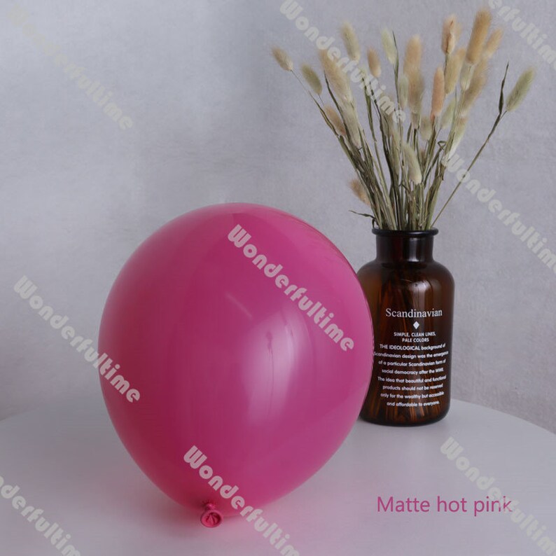 May include: A single matte hot pink balloon. The balloon is round and has a slight sheen. The balloon is sitting on a white surface.
