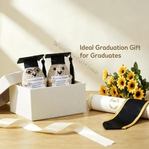 May include: A white gift box contains two crocheted potato figures wearing graduation caps. Each potato holds a card that reads "Positive Potato." A diploma, sunflowers, and a white ribbon are also in the image.